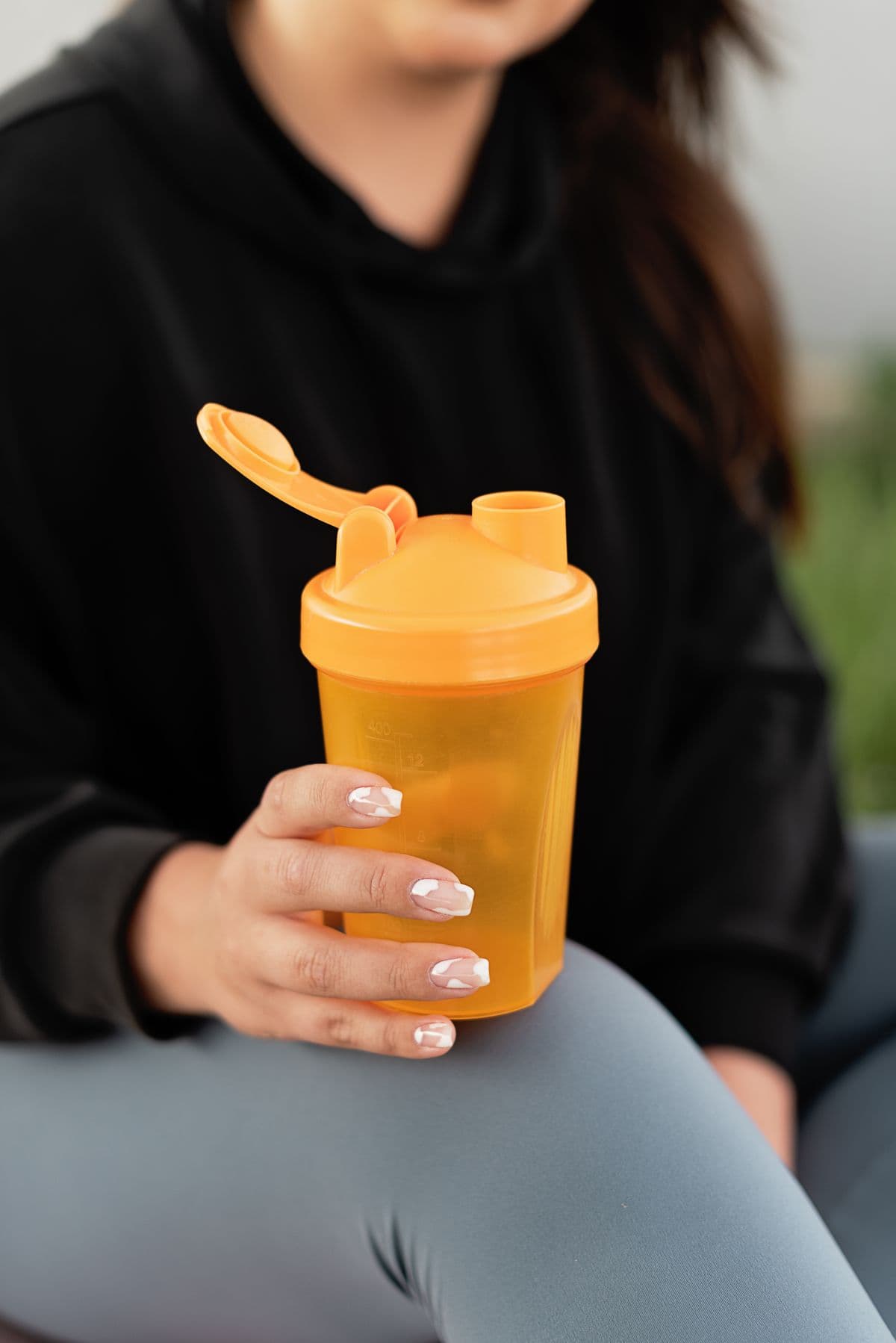 En kvinde holder en orange shaker med en drik